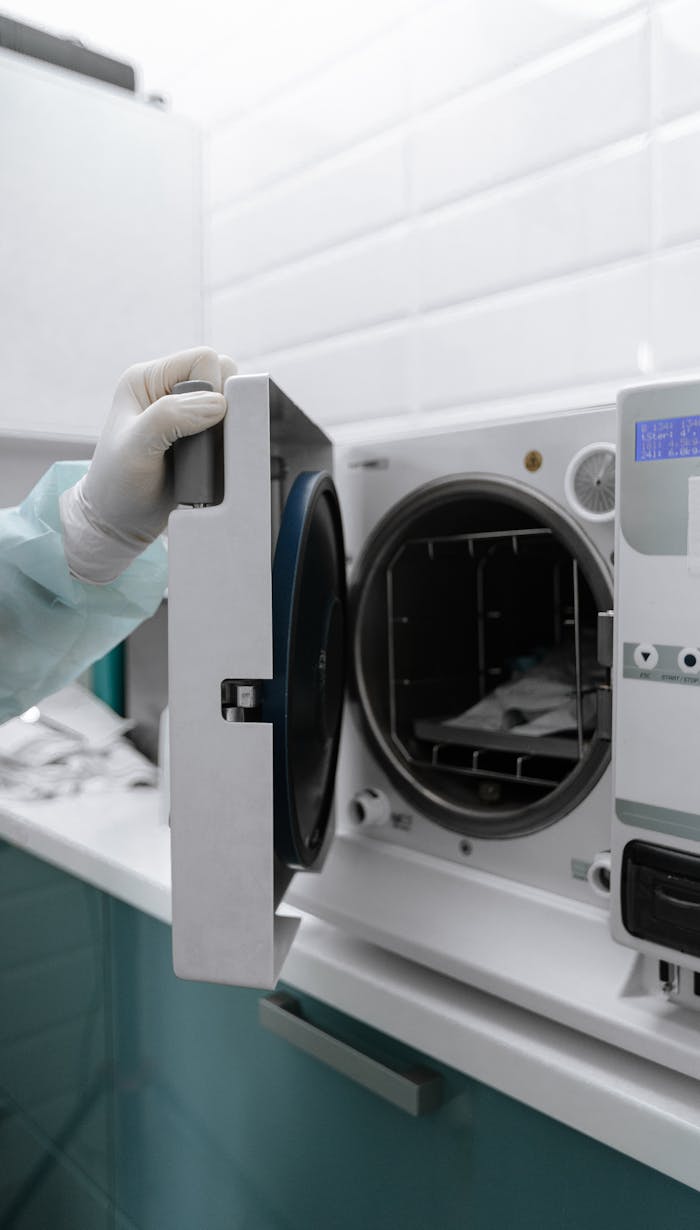 Close-up of a medical autoclave being opened by a gloved hand, used for sterilization.